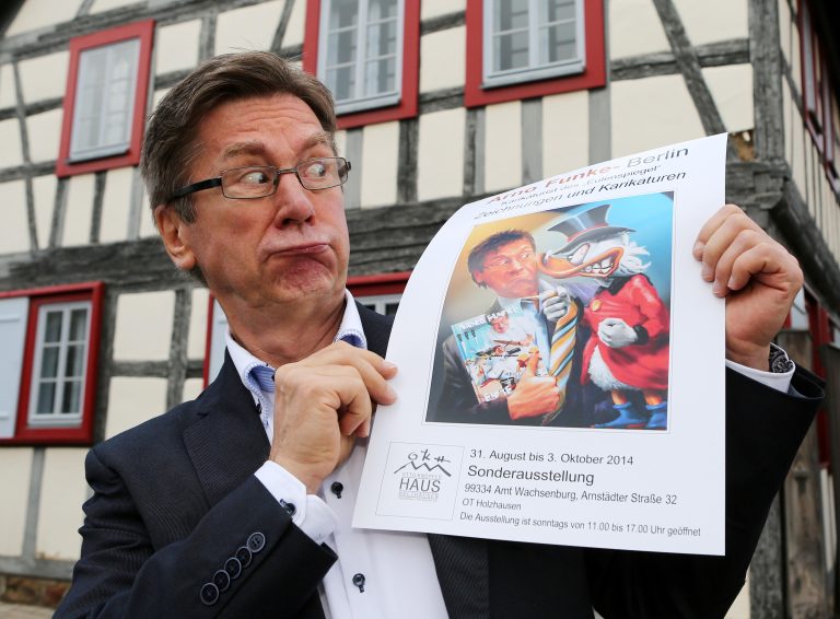 31.08.14 , Holzhausen, der Berliner Künstler Arno Funke (auch Dagobert/ Karikaturist/ Erpresser von Karstadt) stellt im Otto-Knöpfer-Haus Karikaturen aus im Bild: Arno Funke mit dem Plakat der Ausstellung vor dem Otto-Knöpfer-Haus Foto:Karina Hessland
