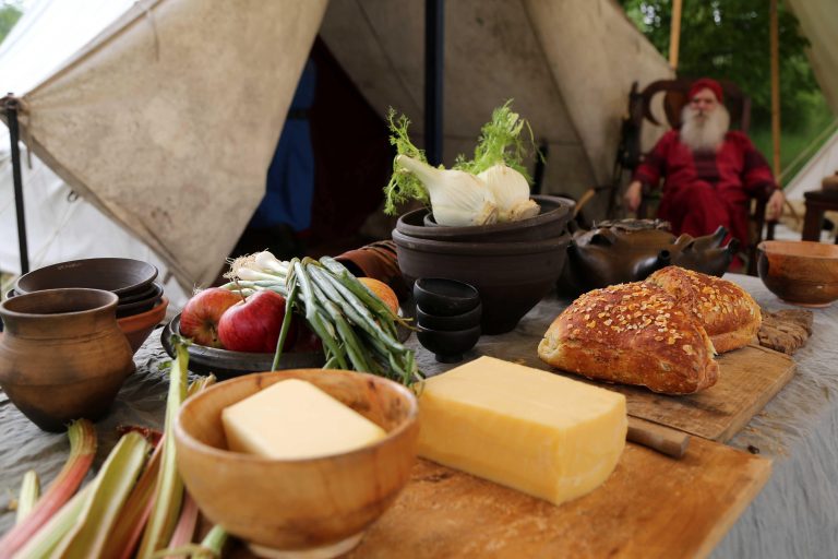 12.05.18 , Westgreussen,  Funkenburg / Germanische Wehrsiedlung / Freilichtmuseumim Bild: Rhabarber, Butter, Käse, Äpfel, Fenchel und Brot auf einem Tisch, im Hintergrund ein alter Mann im historischen Gewand  / Feature Foto: Karina Hessland-Wissel
