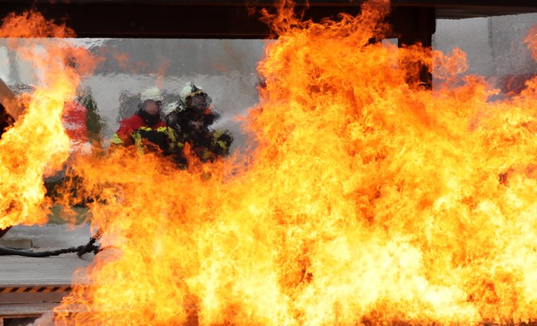 29.03.2022, Erfurt, Flughafen Erfurt-Weimar, der erste mobile Flughafen-Feuersimulator (entwickelt von Florian Funke und der Firma ARFF Services GmbH) macht hier Station fuer ein Training, die Flughafenfeuerwehren koennen damit unter realen Bedingungen trainieren im Bild: Feuerwehrmaenner loeschen den Brand Foto: Karina Hessland-Wissel