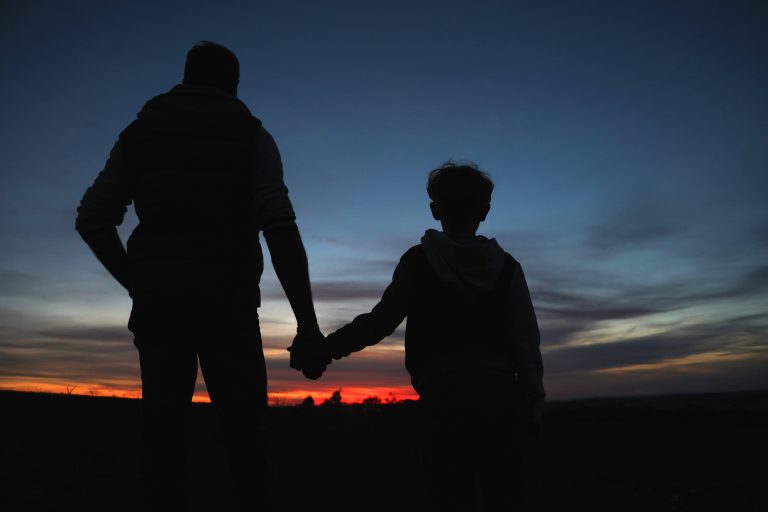 01.10.2023, Ostramondra, Vater und Sohn sehen sich den  Sonnenuntergang an, der Himmel leuchtet rot 
Foto: Karina Hessland-Wissel