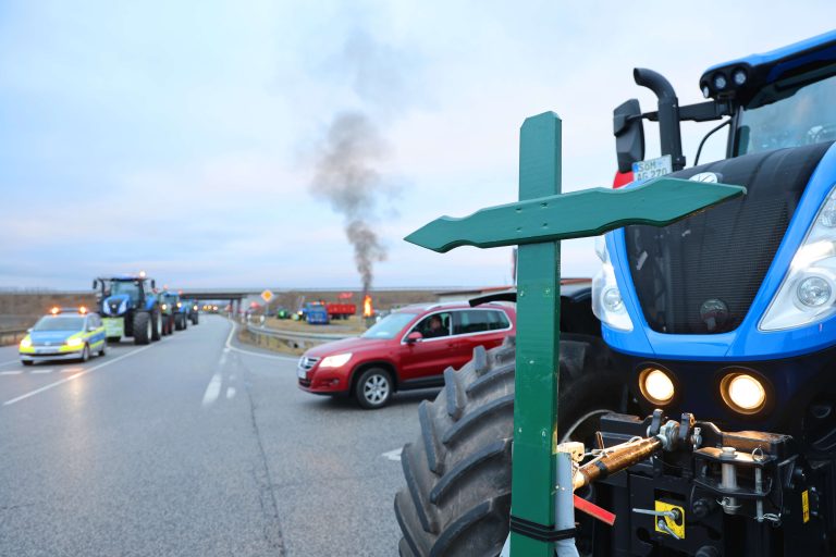 31.01.2024, Koelleda, im Rahmen der Bauernproteste gegen die Streichungen von Subventionen hat der Thueringer Bauernverband dazu aufgerufen, die Autobahnauffahrten von 08.00 - 13.00 Uhr zu blockierenim Bild: Traktoren stehen in der Auffahrt Koelleda in Richtung Sangerhausen zur Autobahn A71 - an der Front eines Traktors ist ein gruenes Kreuz befestigt, im Hintergrund brennt ein Mahnfeuer Foto: Karina Hessland-Wissel